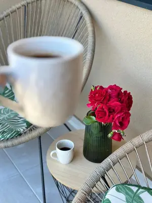 a cup of coffee and a vase of red roses at Lenka Lux VB in Vrnjačka Banja