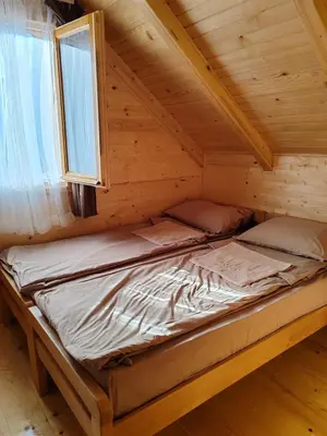 a bed in a log cabin with a window at Tosic etno kamp in Pirot