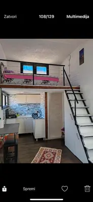 a living room with a staircase and a room with a table at Tosic etno kamp in Pirot