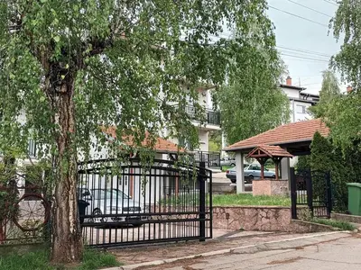 a black gate with a tree in front of a house at Apartman Djukic Sokobanja 1 in Soko Banja