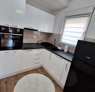 a kitchen with white cabinets and a black refrigerator at Apartman WIN Sokobanja in Soko Banja