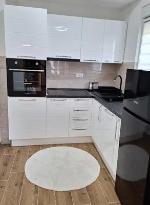 a kitchen with white cabinets and a rug on the floor at Apartman WIN Sokobanja in Soko Banja