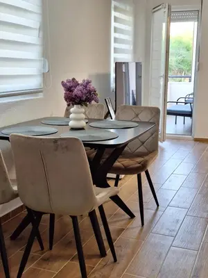 a dining room table with chairs and a vase of flowers at Apartman WIN Sokobanja in Soko Banja