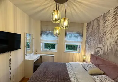 a bedroom with a bed and a television and windows at Violet deluxe in Niš