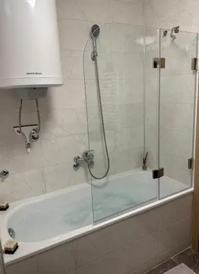 a bath tub with a shower with a glass door at Violet deluxe in Niš