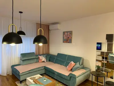 a living room with a green couch and two pendant lights at Violet deluxe in Niš