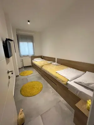 a room with three beds and two yellow rugs at Mint House in Niš