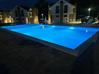 a large blue swimming pool at night at Vila-L&M- Royal in Lipova