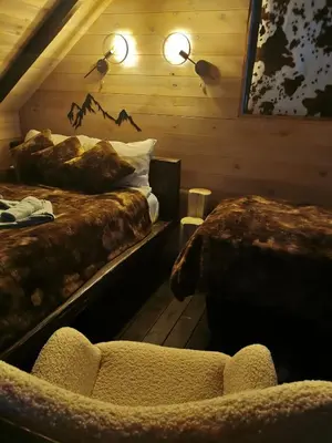 a room with two beds and a chair in it at Ski & Spa Bungalows in Kopaonik