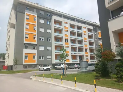 an apartment building with cars parked in a parking lot at Apartman Elizabet in Pirot