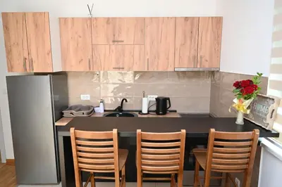 a kitchen with a counter with chairs and a sink at Apartman A&A lux in Vrnjačka Banja