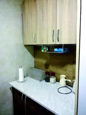 a kitchen counter with wooden cabinets and a white counter top at Lux aprtman in Leskovac