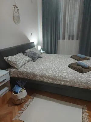 a bedroom with a bed with a couch and a window at Apartman La Viva Sokobanja in Soko Banja
