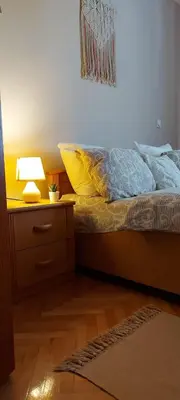 a bedroom with a bed and a nightstand with a lamp at Apartman La Viva Sokobanja in Soko Banja