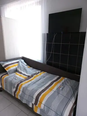 a bed with a black and yellow comforter and a window at Studio apartman Beus in Kuršumlija