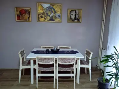 a dining room table with chairs and pictures on the wall at LUX Apartman in Leskovac