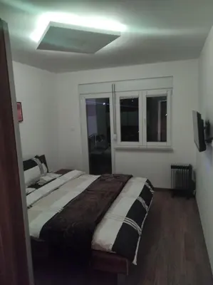 a bedroom with a bed and two windows at Cera premium apartment in Soko Banja