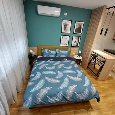 a bedroom with a bed with a blue comforter at Studio Vera in Kruševac
