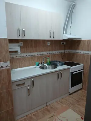 a kitchen with white cabinets and a sink at Apartman AM Mladenović in Vranje