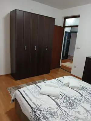 a bedroom with a large bed and a wooden cabinet at Apartman AM Mladenović in Vranje