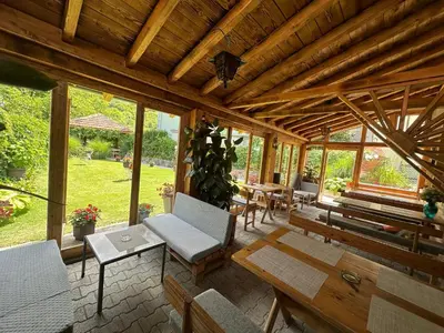 a screened in porch with chairs and tables at Villa Veljković - Sobe & apartmani 
