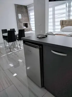 a kitchen with a counter with a dishwasher and chairs at Lela lux in Jošanička Banja