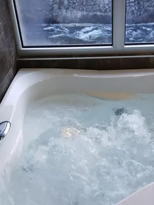 a bath tub filled with water next to a window at Lela lux in Jošanička Banja