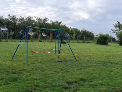 an empty swing set in a grass field at Apartmani Feliks in Resavica