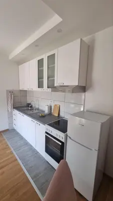 a kitchen with white cabinets and a white refrigerator at Apartman Djordjevic in Soko Banja