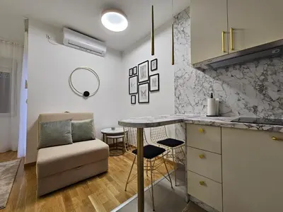 a kitchen with a counter and a table and chairs at Studio apartman Gold in Vrnjci