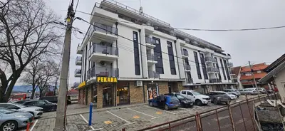 a tall building with cars parked in a parking lot at Studio apartman Gold in Vrnjci