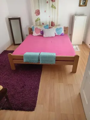 a bedroom with a large bed with a pink blanket at Palamar in Kuršumlija