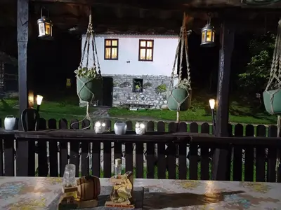 a table in front of a house with lights at Seosko Domaćinstvo Jevtić in Ždraljica