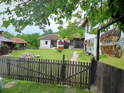 a fence in front of a house with a sign at Seosko Domaćinstvo Jevtić in Ždraljica