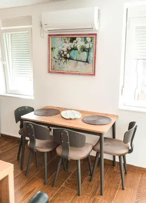a dining room table with chairs and a painting on the wall at Apartman Leskovčanka in Leskovac