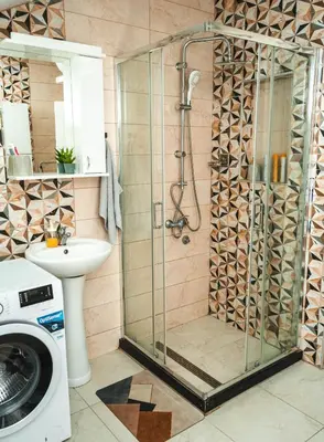 a shower in a bathroom with a sink and a washing machine at Apartman Leskovčanka in Leskovac