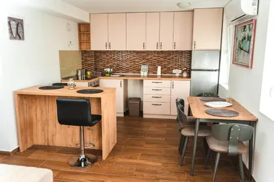 a kitchen with a wooden table and chairs in it at Apartman Leskovčanka in Leskovac
