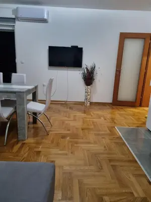 a living room with a table and a television on a wall at Apartman BN in Vrnjačka Banja