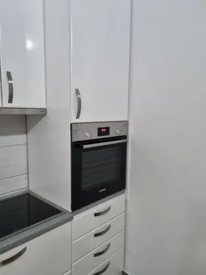 a kitchen with a black oven and white cabinets at Apartman BN in Vrnjačka Banja