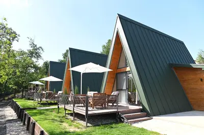 a house with a black roof with chairs and umbrellas at Horizonti in Vrmdža