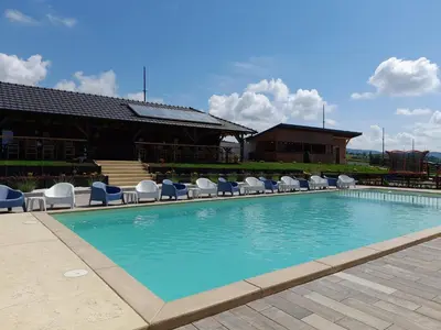 a large swimming pool with chairs and a building at Horizonti in Vrmdža