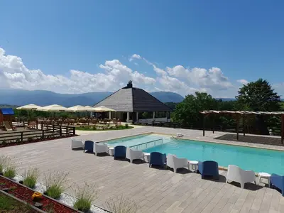 a swimming pool with chairs and a gazebo at Horizonti in Vrmdža
