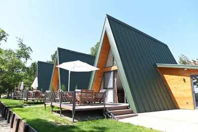 a house with a black roof with chairs and an umbrella at Horizonti in Vrmdža