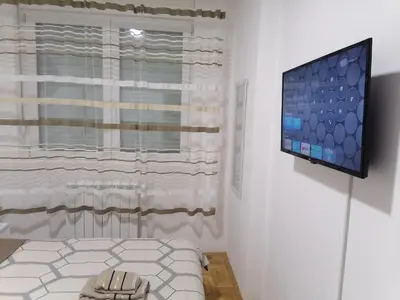 a room with a bed and a television on a wall at Apartman Zapadni Kej Pirot in Pirot