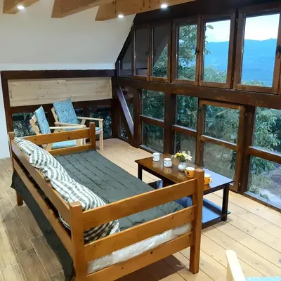 a room with a bed and a table and windows at Magarija 1 in Dimitrovgrad