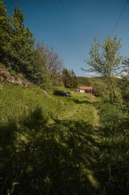 a grassy hill with a car parked in a field at Kuca Lula Stara planina in Pirot