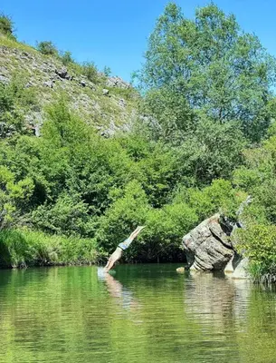 a person diving into a river with a rock in the water at Kuca Lula Stara planina in Pirot