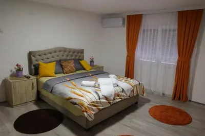 a bedroom with a bed with yellow and orange pillows at Apartman Nikolić in Kuršumlija