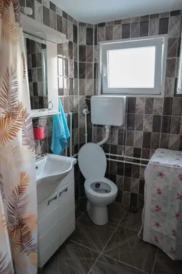 a bathroom with a toilet and a sink and a window at Apartman Nikolić in Kuršumlija