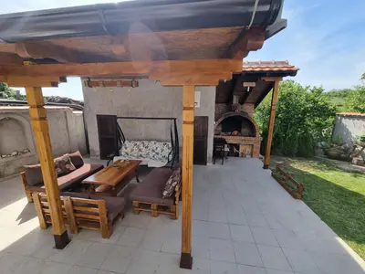 a wooden pergola with a table and a fireplace at Vila MINJA in Soko Banja
